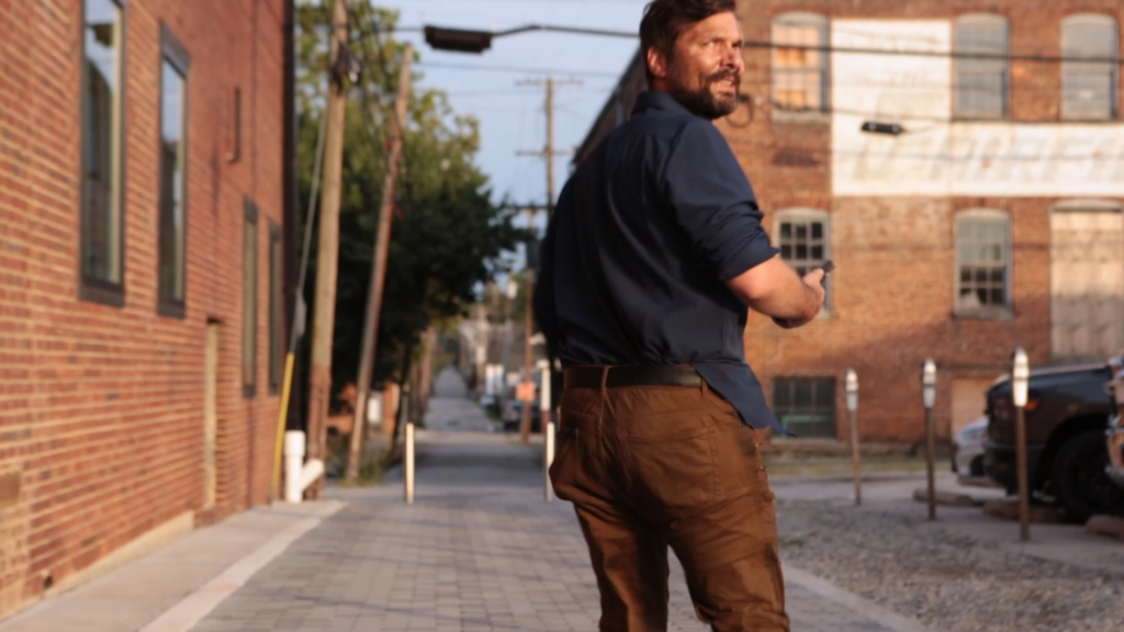 Snapshot of Word and Deed teaser Miller running a city back street